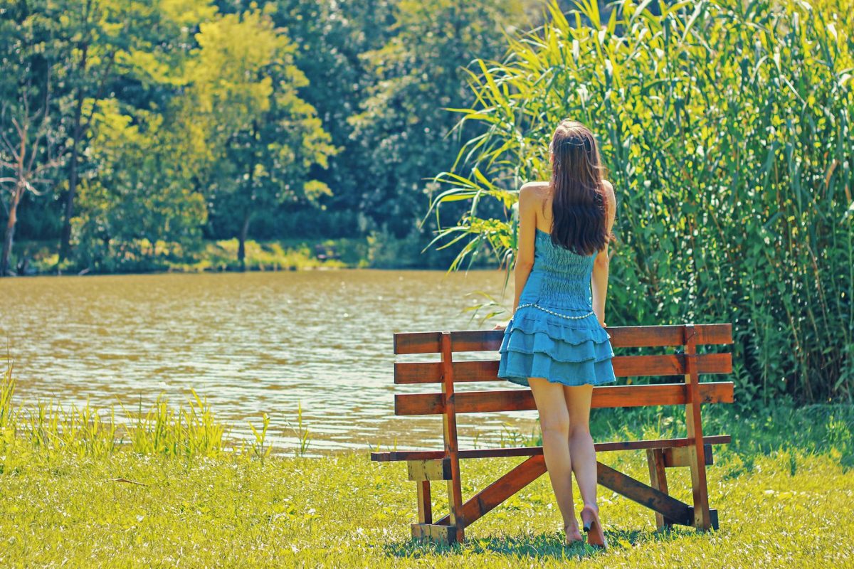 full length rear view of a woman overlooking calm lake