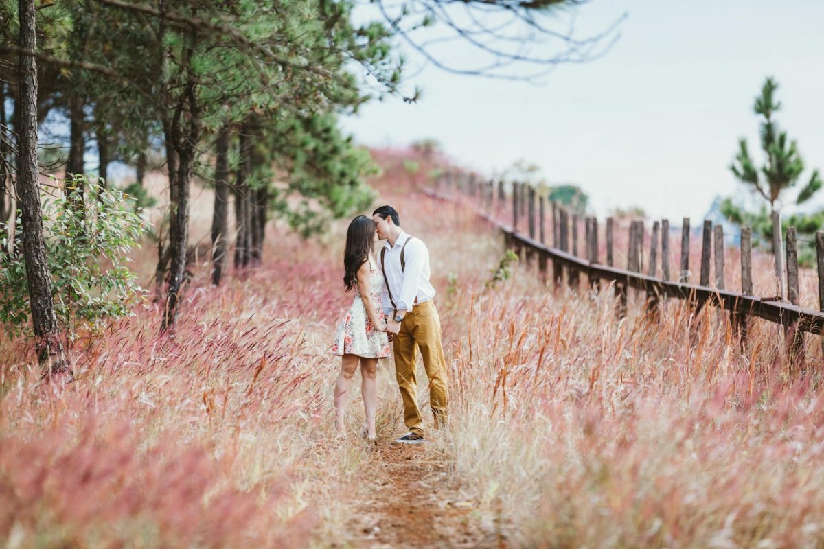 couple kissing beside trees
