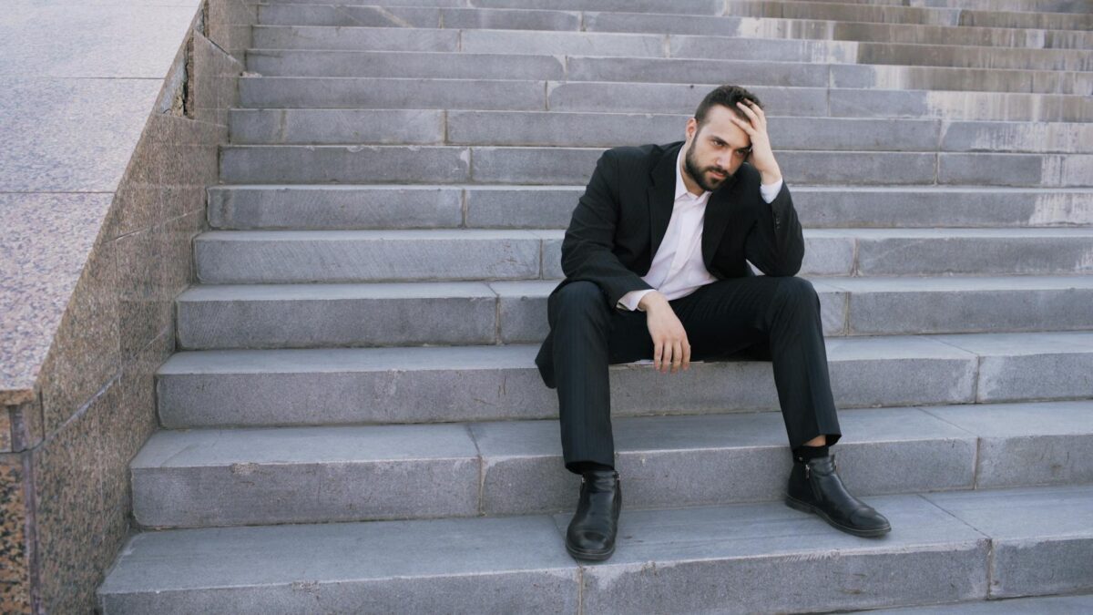 stressed businessman sitting on urban stairs