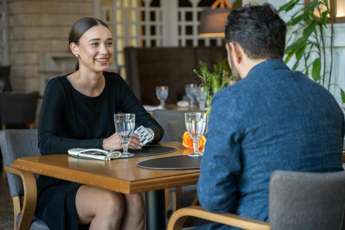 woman in black long sleeve dress sitting in front of a man